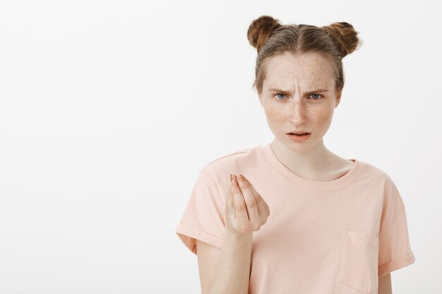 Frustrated and displeased teenage girl posing against the white wall