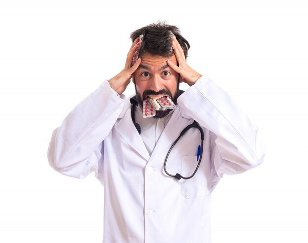 Frustrated doctor with pills over white background