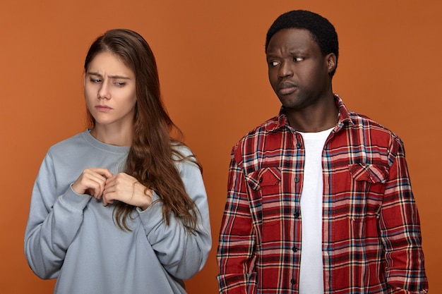 Free photo frustrated european 20 year old girl feeling nervous because of disagreement with her dissapointed displeased african american boyfriend. people, ethnicity, relationships, quarrel and problems concept