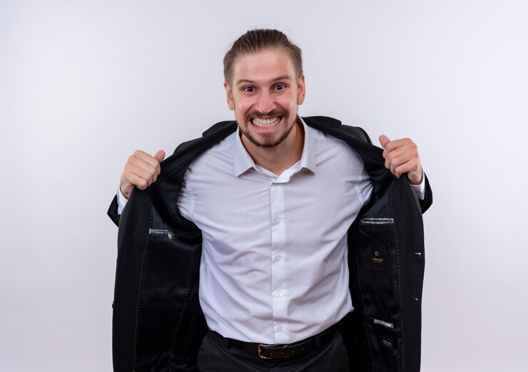 Free Photo frustrated handsome business man wearing suit looking at camera going wild by taking off his suit standing over white background