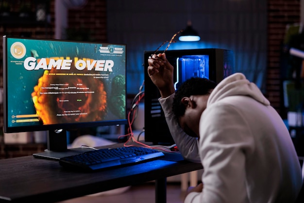 온라인 슈팅 비디오 게임을 잃는 좌절된 스트리머는 네온 불빛으로 컴퓨터에서 경쟁합니다. 남성 게이머 스트리밍 액션 게임 플레이 및 잃어버린 슈팅 챔피언십에 대해 슬퍼합니다.