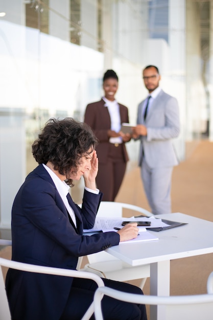 Impiegato femminile stanco frustrato che lavora con i documenti