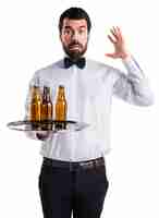 Free photo frustrated waiter with beer bottles on the tray