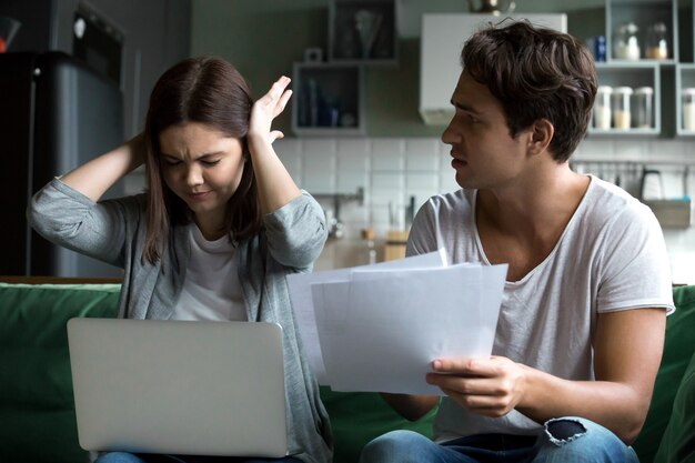 Frustrated wife disagreeing with angry husband blaming of overspending money