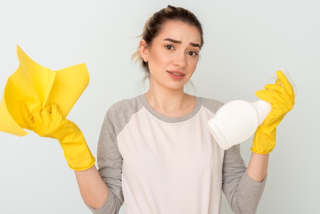 Frustrated woman holding cleaning solution and cloth