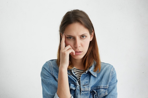 Donna frustrata che tiene il dito sulla tempia, cercando di concentrarsi sul lavoro ma sentendosi affaticata, guardando con espressione stanca esausta