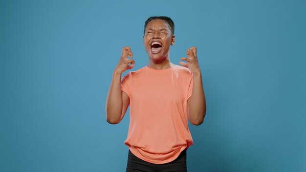Frustrated woman screaming in front of camera in studio. Person with angry facial expression yelling loud and feeling furious, standing over isolated background. Adult with rage problem