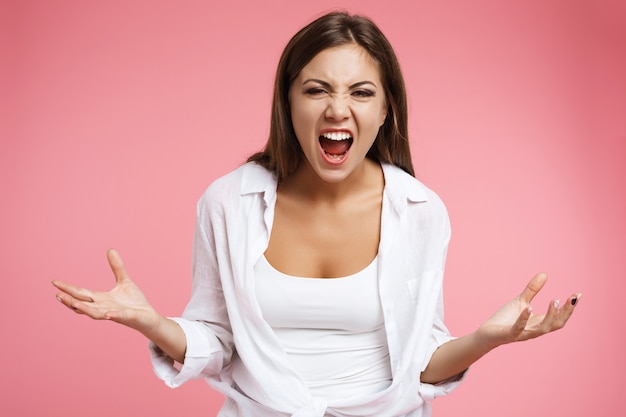 Frustrated woman screams looking straight holding hands up