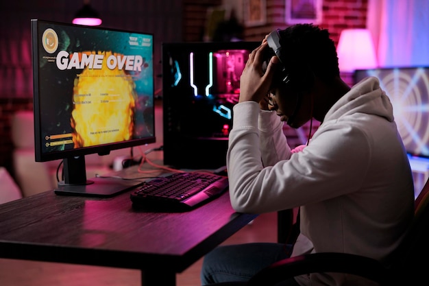 オンラインビデオゲームに負けた欲求不満の若い成人は、ネオンライト付きのコンピューターで競争をします。男性ゲーマーがアクションゲームプレイをストリーミングし、射撃選手権の敗北に悲しみを感じています。