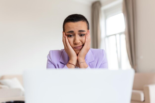 Frustrated young African American businesswoman working on a laptop sitting at desk in office