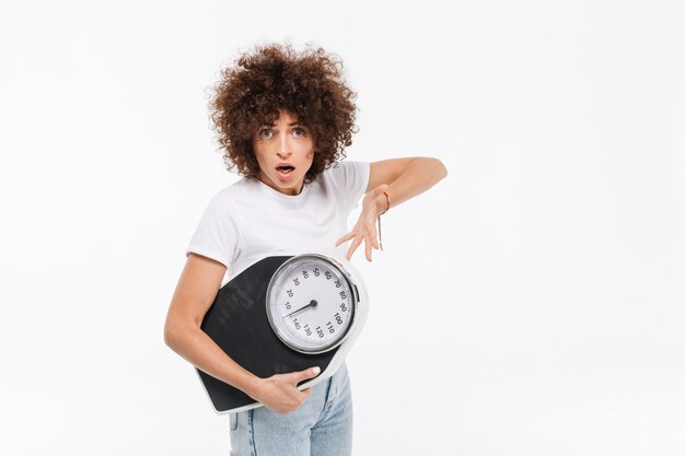 Frustrated young casual woman pointing at weights