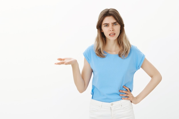 Frustrated young woman asking why, can't understand shrugging concerned