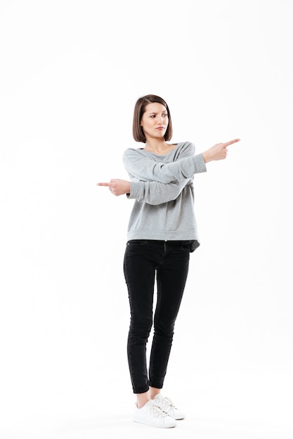 Frustrated young woman pointing fingers both ways