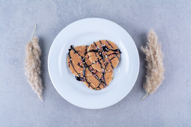 Free photo a frying pan of round ruddy waffle with sprinkles and cream