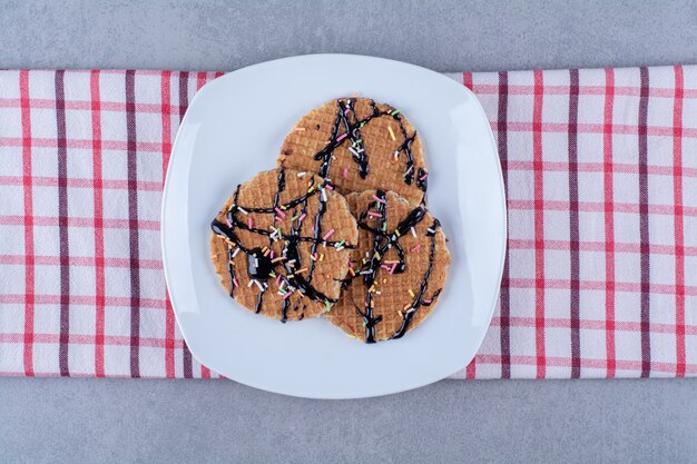 A frying pan of round ruddy waffle with sprinkles and cream .