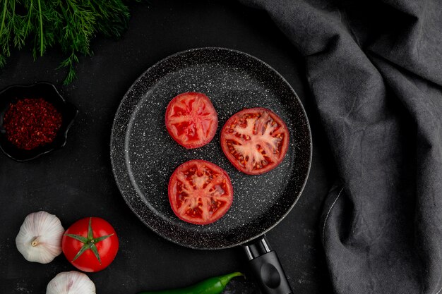  frying pan of tomatoes with garlic fennel and spices on black table