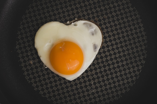 Free photo frying pan with fried egg with heart shape