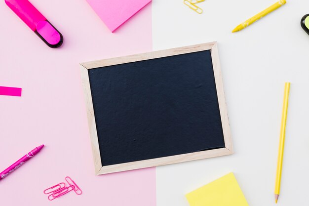 Free photo fuchsia and yellow stationery around chalkboard