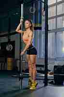 Free photo full body image of fitness female model holds barbell over trx straps stand in a gym club.