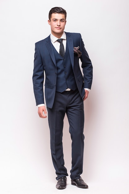 Full body portrait of a businessman in suit standing on isolated white wall