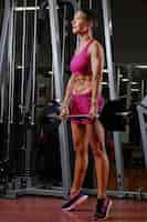 Free photo full body portrait of sporty middle age female with short hair holds the barbell in a gym club.