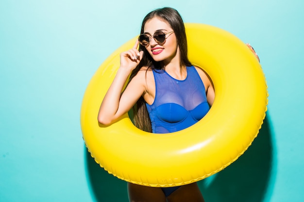 Full body sexy woman in swimsuit with yellow inflatable ring isolated over green wall