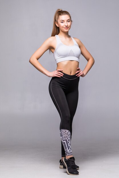 Full body of young cheerful smiling woman in sports wear, isolated