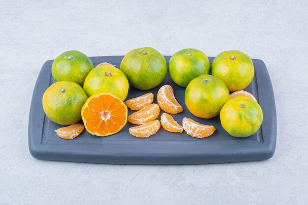 Full dark cutting board of sour tangerines on white background. High quality photo