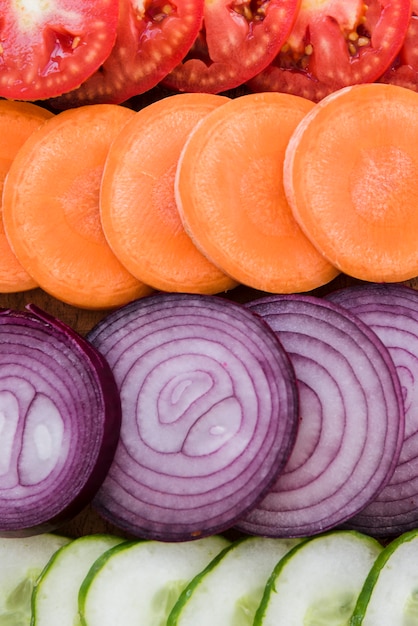 Full frame of tomatoes; carrot; onion and cucumber slices backdrop