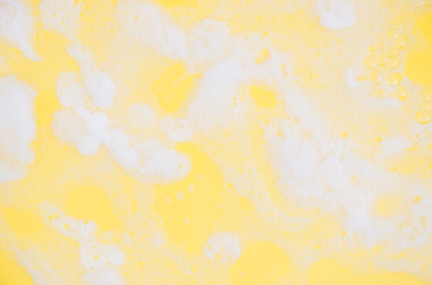 Free photo full frame of white soap sud on yellow background