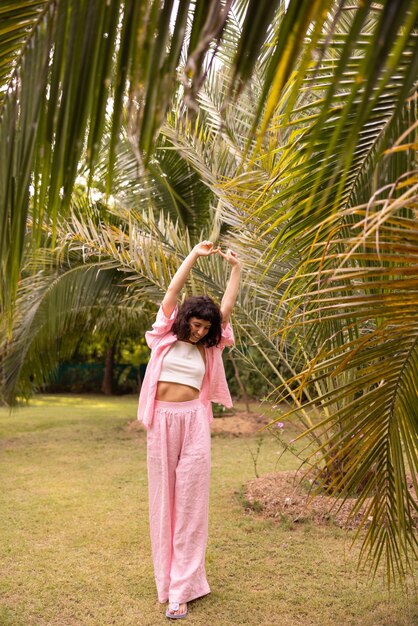 In full growth slim young caucasian brunette in pink clothes stretches arms up looking away outdoors Beauty people emotions and summer vacation concept