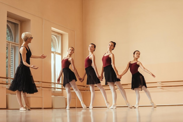 Full length of ballet teacher ad group of ballerinas rehearsing at dance studio