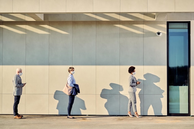 Full Length Of Business People With Protective Face Masks Waiting In A Line Outdoors