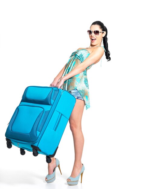 Full length of casual woman holds the heavy travel suitcase