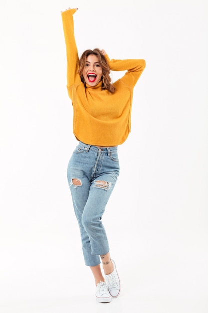 Free photo full length cheerful woman in sweater rejoices  over white wall