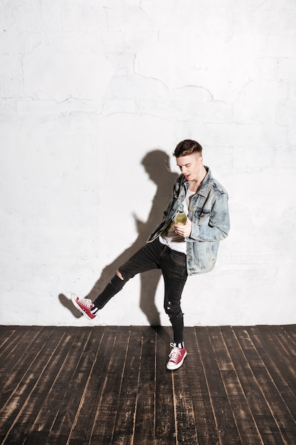 Full length of cheerful young man drinking champagne and dancing