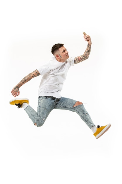 Free photo full length of handsome young man taking selfie while jumping