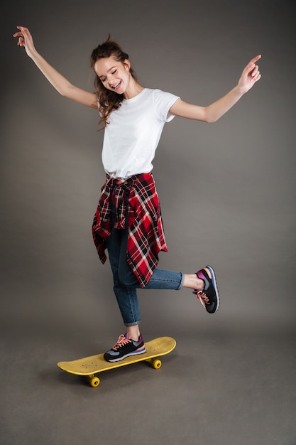 Integrale della ragazza spensierata felice che guida sullo skateboard