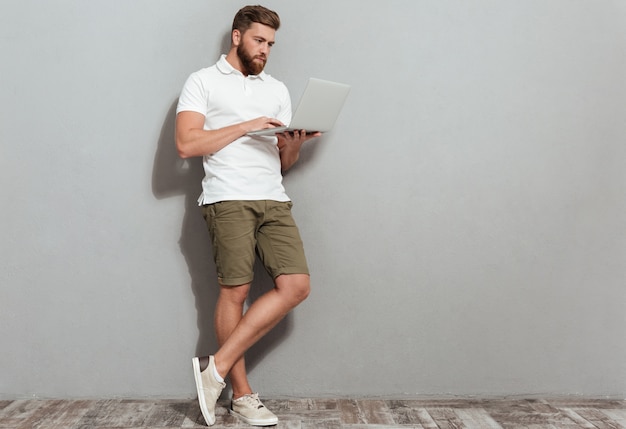 Full length image of bearded man using laptop computer