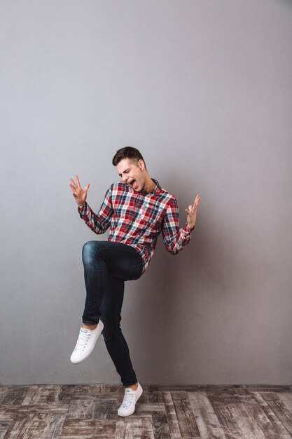 Full length image of Cheerful screaming man in shirt and jeans rejoice