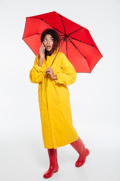 Full length image of confused african woman in raincoat