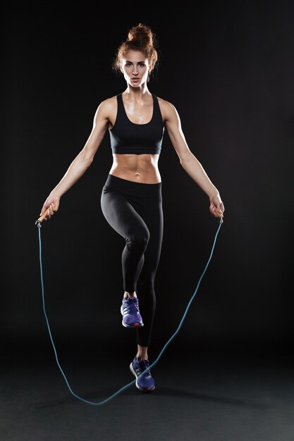 Полная длина образ фитнес женщина прыгает со скакалкой