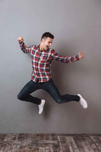 Full length image of Happy man in shirt and jeans jumping