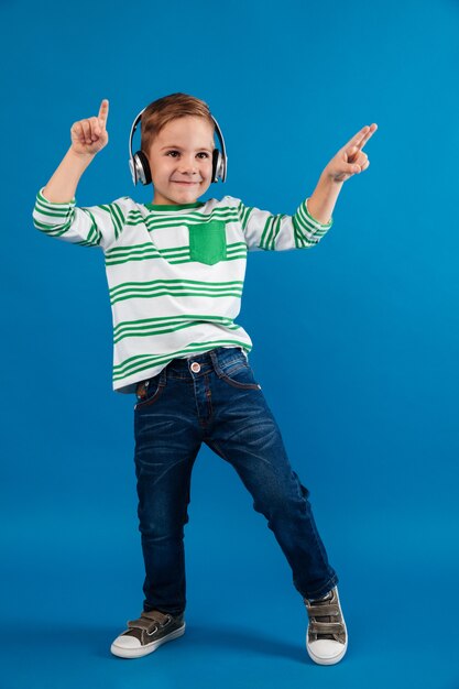 Full length image of happy young boy listening music