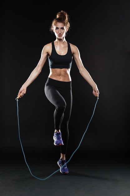 Бесплатное фото Полная длина образ фитнес женщина прыгает со скакалкой