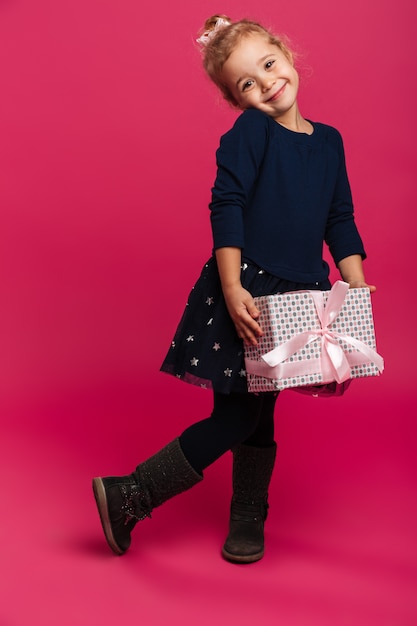 Full length image of Pleased young girl holding gift box