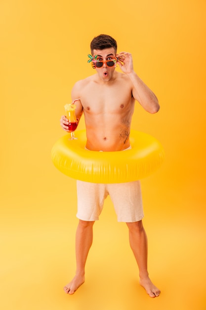 Full-length image of Shocked naked man in shorts and sunglasses