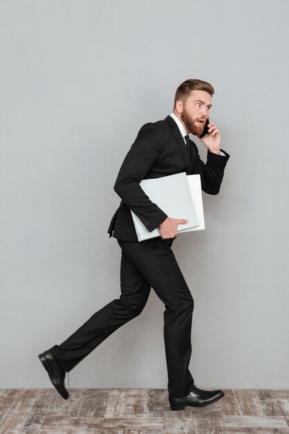 Full length image of a surprised bearded man in suit