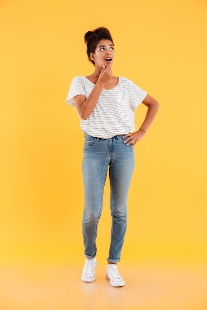 Full-length image of surprised lady looking up at copy space isolated over yellow