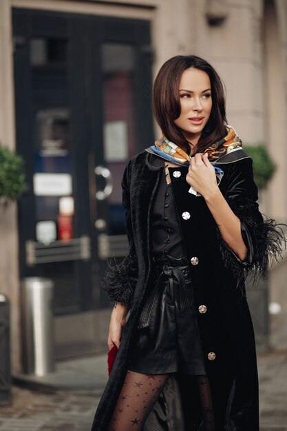 Full length photo of beautiful elegant woman walking on the street while wearing silk scarf on her head. Beauty and fashion concept